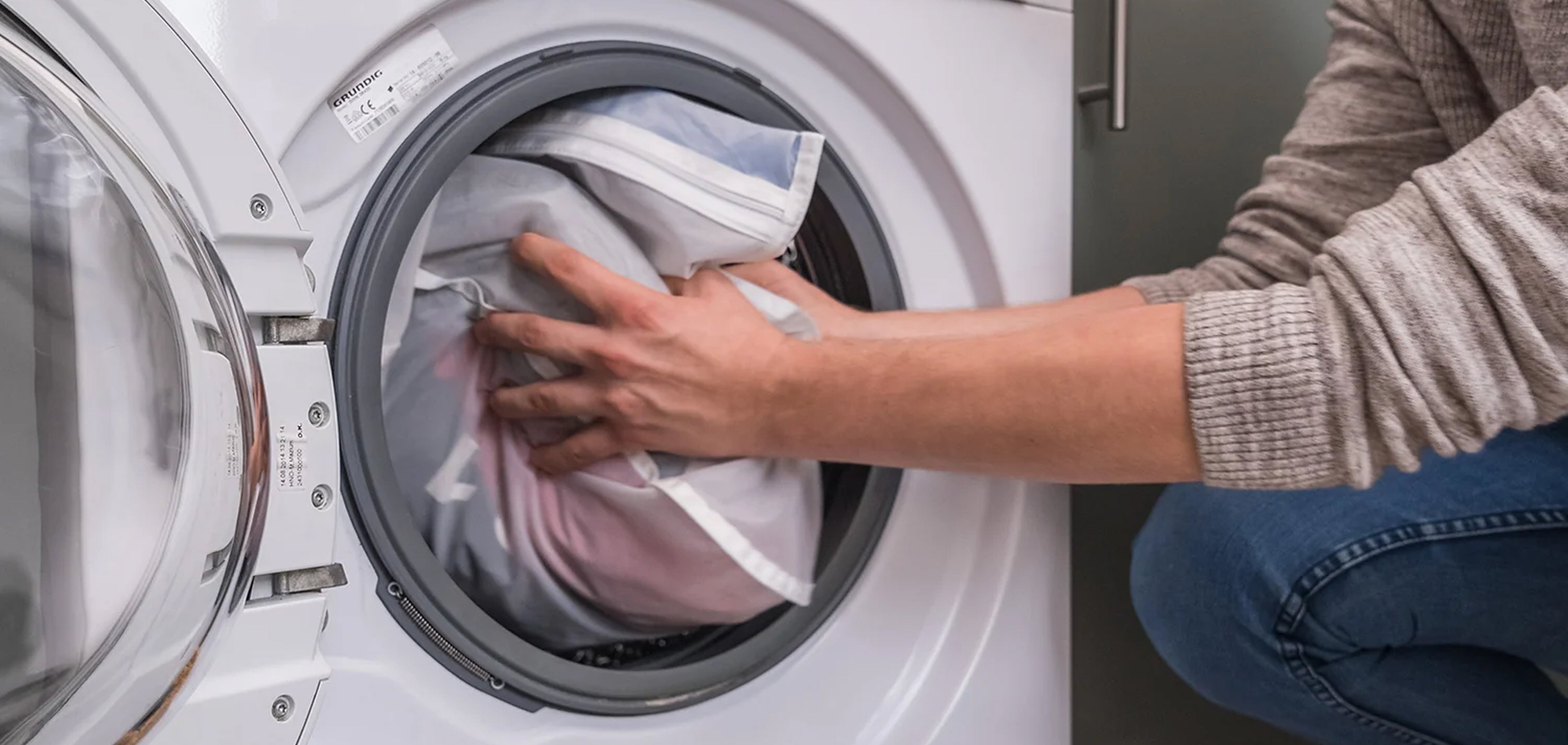 Person loading laundry into a washing machine